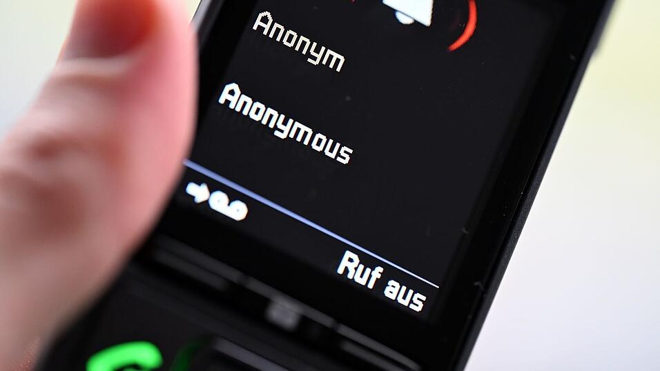 ILLUSTRATION - Ein Mann hält ein Festnetz-Telefon, auf dem ein anonymer Anruf eingeht (gestellte Szene).