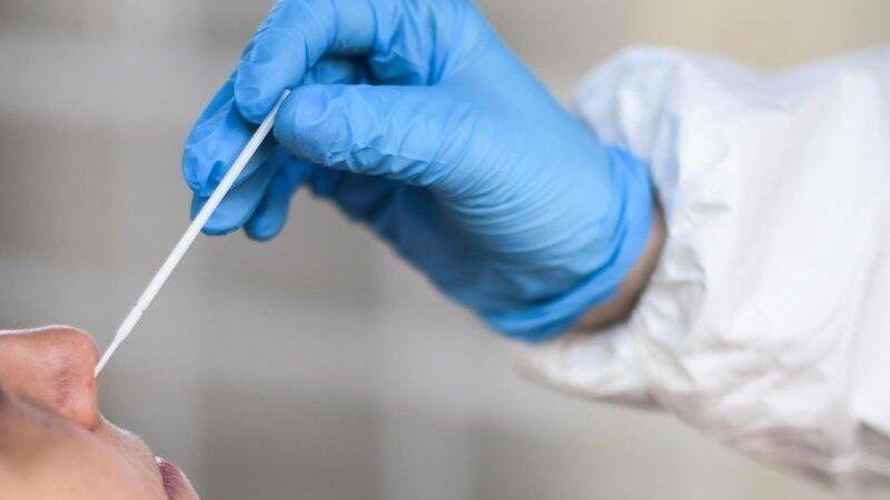 Ein medizinischer Mitarbeiter entnimmt einer Frau f&uuml;r einen Corona-Test einen Abstrich.