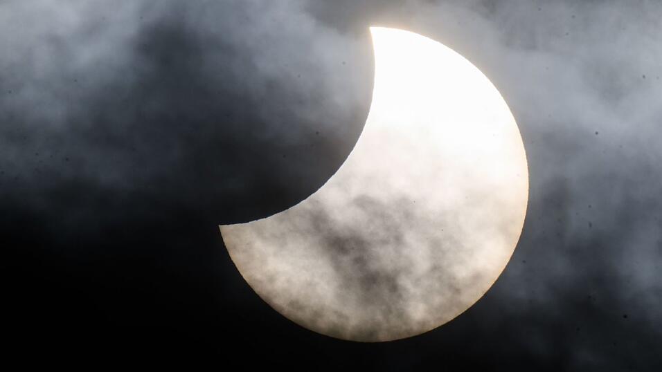 Eine partielle Sonnenfinsternis ist zwischen Wolken am Himmel zu sehen. (Archivbild) Eine partielle Sonnenfinsternis ist zwischen Wolken am Himmel zu sehen. (Archivbild)
