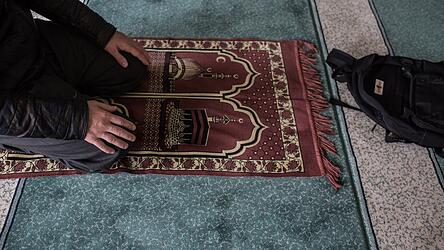 Ein Muslim kniet in einer Moschee einem Gebetsteppich. Ein Muslim kniet in einer Moschee einem Gebetsteppich.