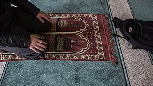 Ein Muslim kniet in einer Moschee einem Gebetsteppich. Ein Muslim kniet in einer Moschee einem Gebetsteppich.