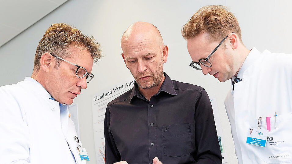 Prof. Lukas Prantl (links) und Prof. Sebastian Geis begutachten den Heilungsverlauf und die Beweglichkeit der linken Hand von Christian R. Prof. Lukas Prantl (links) und Prof. Sebastian Geis begutachten den Heilungsverlauf und die Beweglichkeit der linken Hand von Christian R.