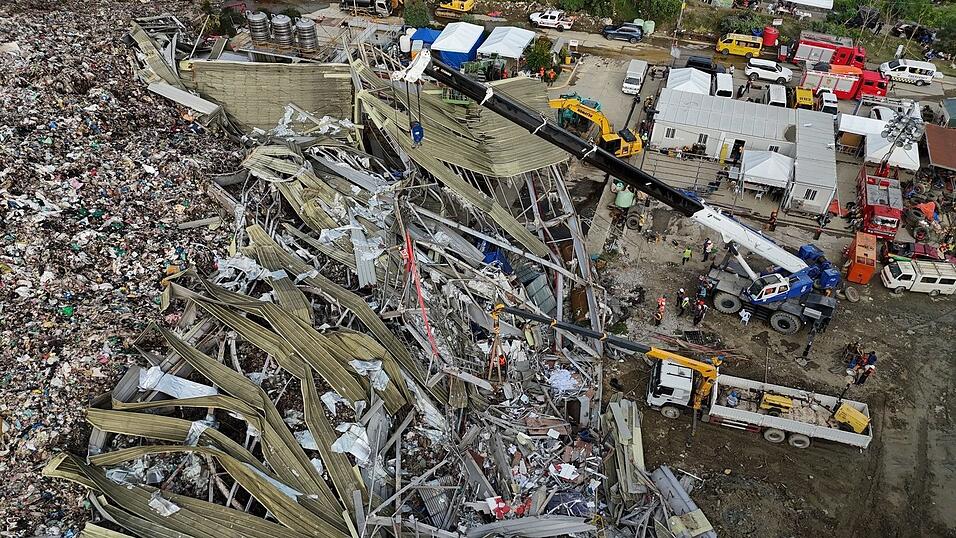 Die Einsatzkr&auml;fte suchen unter anderem mit einem Kran in den Abfall-Massen.