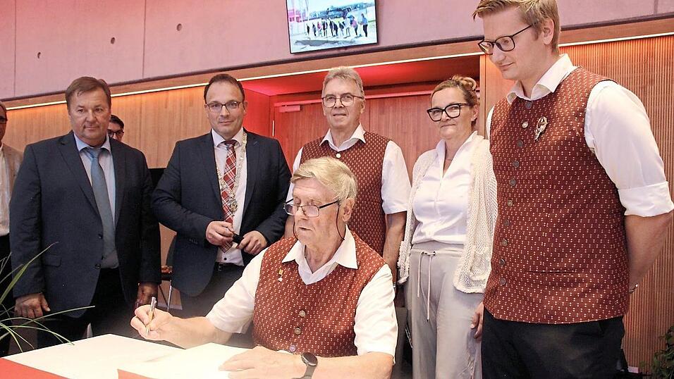 Reinhard Lesinski (sitzend), Sepp Blaha (Dritter von rechts) und Andreas Sperlich (rechts) tragen sich ins Goldene Buch ein.