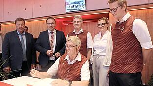 Reinhard Lesinski (sitzend), Sepp Blaha (Dritter von rechts) und Andreas Sperlich (rechts) tragen sich ins Goldene Buch ein.