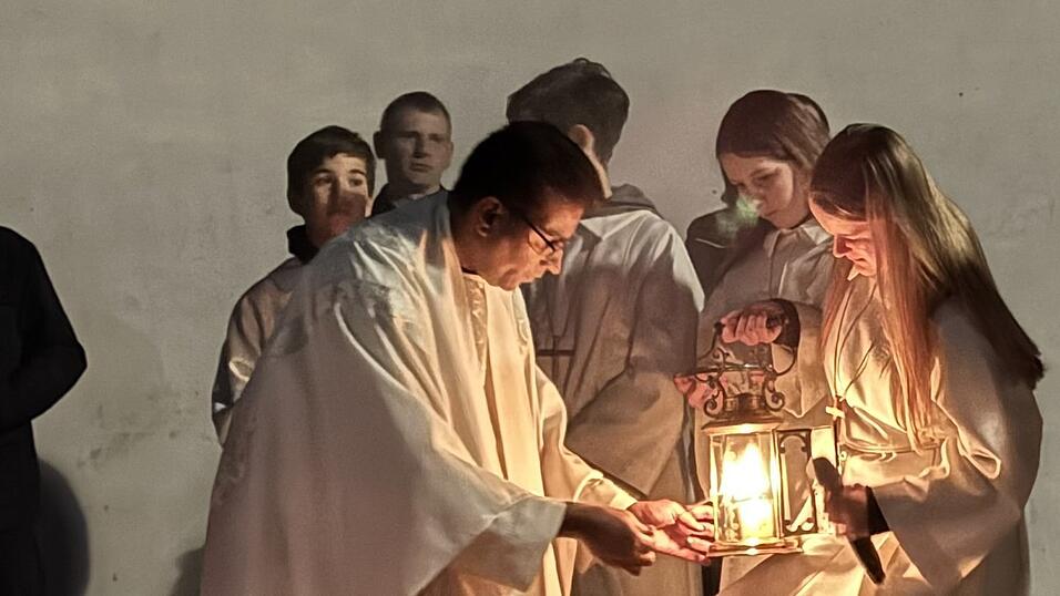 Pfarrer Jis Mangaly holt das Licht für die Osterkerze von entzündeten Holzstoß aus der Feuerschale. Pfarrer Jis Mangaly holt das Licht für die Osterkerze von entzündeten Holzstoß aus der Feuerschale.