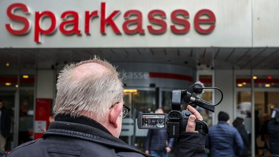 Ein Medienvertreter steht mit einer Kamera vor der Sparkassenfiliale in Buer.