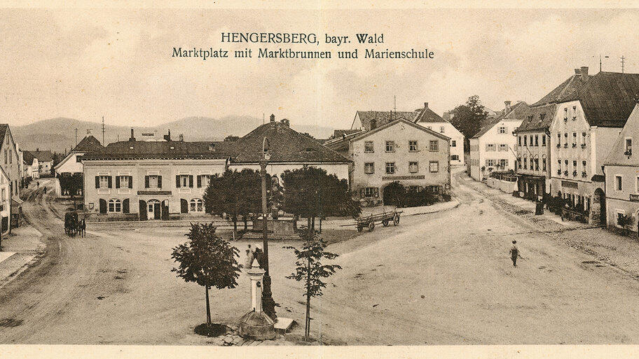 Die seltene Panorama-Ansichtskarte vom &auml;ltesten Markt Bayerns, Hengersberg im Landkreis Deggendorf, zeigt den Marktplatz aus s&uuml;dlicher Richtung. Der vermutlich vom Fotografen leer gefegte Marktplatz erscheint &uuml;berdimensioniert. Wenn jedoch die gro&szlig;en Viehm&auml;rkte stattfanden, dann platzte er aus allen N&auml;hten.