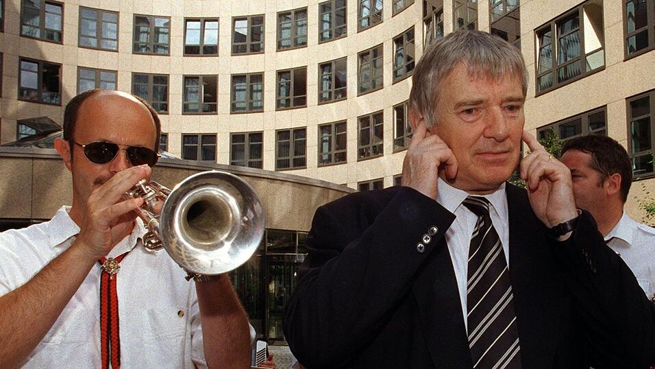 Der damalige Bundesminister Otto Schily (r) h&auml;lt sich die Ohren zu, w&auml;hrend ein Trompeter zur offiziellen Einweihungsparty des Bundesinnenministeriums in Berlin am 13. Juli 1999 aufspielt. Das Innenressort war die erste Beh&ouml;rde, die nach dem Regierungsumzug komplett in Berlin arbeitete.