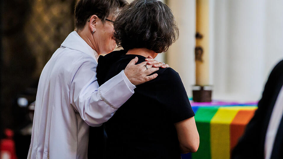Zwei Menschen stehen Arm in Arm bei einem Gottesdienst in der St. Marienkirche. Zwei Menschen stehen Arm in Arm bei einem Gottesdienst in der St. Marienkirche.