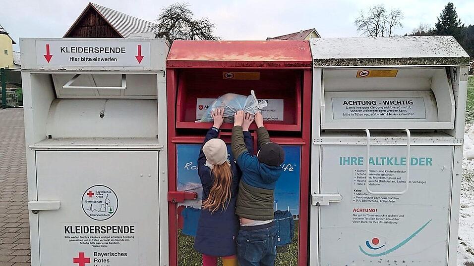 Und rein damit: Die zwei Kinder entscheiden sich f&uuml;r den Container der Malteser.