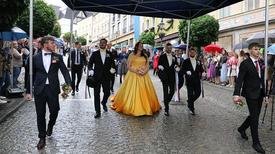 Wie aus Eimern sch&uuml;ttete es am sp&auml;ten Dienstagnachmittag beim Burschen- und Brautzug. Spontan improvisierten die Burschen und sch&uuml;tzten das Pfingstbrautpaar mit seinen Begleitern vor dem Regen. Fotos: Lisa Rackl/Pia Kollmer