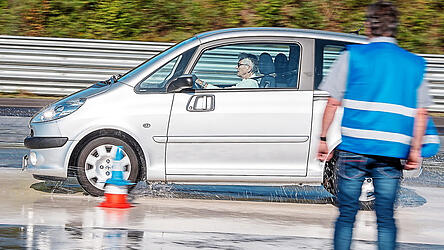 Eine Seniorin fährt mit ihrem Auto über eine Teststrecke.