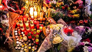 Ein Blumen- und Kerzenmeer erinnert an Tote und Verletzte in der N&auml;he des Brandortes.
