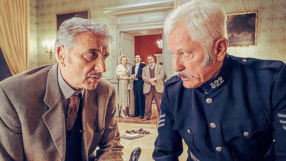 Chief Inspector Francis Lightmyer (Udo Wachtveitl, links) und Constable Ivor Partridge (Miroslav Nemec, rechts) untersuchen Arthur im Kaminzimmer. Lady Bantam (Sunnyi Melles), Charles (Ferdinand Hofer) und Dr. Mallard (Alexander Hörbe, rechts hinten) beobachten sie. Chief Inspector Francis Lightmyer (Udo Wachtveitl, links) und Constable Ivor Partridge (Miroslav Nemec, rechts) untersuchen Arthur im Kaminzimmer. Lady Bantam (Sunnyi Melles), Charles (Ferdinand Hofer) und Dr. Mallard (Alexander Hörbe, rechts hinten) beobachten sie.