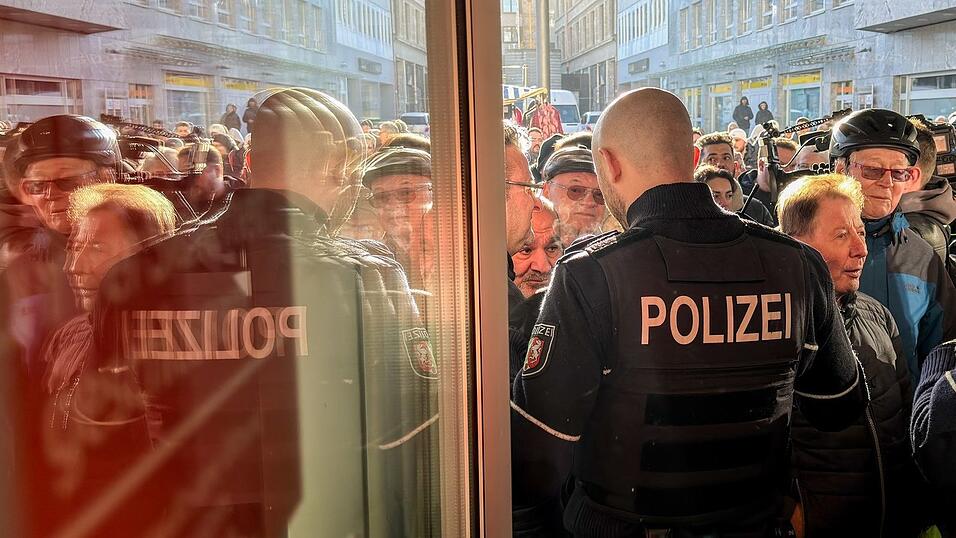 Polizisten sichern den Eingang der Sparkassenfiliale in Gelsenkirchen, vor der viele besorgte Kunde stehen und Informationen nach dem Einbruch in den Tresorraum verlangen.