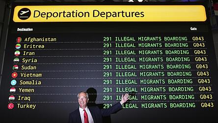 Der britische Rechtspopulist Nigel Farage posiert vor einer Attrappe einer Abflugtafel, auf der verschiedene Länder aufgelistet sind mit dem Hinweis „Illegale Zuwanderer steigen ein“. Er will Asylsucher abschieben.