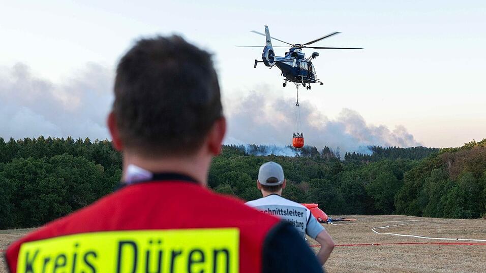 Ein L&ouml;schhubschrauber bek&auml;mpft am Donnerstagabend die Flammen des Waldbrandes Nahe H&uuml;rtgenwald.