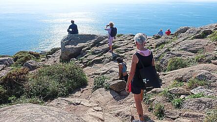 Endlich angekommen am 'Ende der Welt': Pilger auf dem Trampelpfad vom Leuchtturm zum Meer, um sich nach den Strapazen auszuruhen
