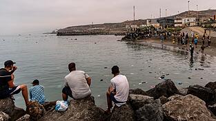 Migranten blickten von Felsen aus, während andere aus der spanischen Enklave Ceuta nach Marokko zurückkehrten. Migranten blickten von Felsen aus, während andere aus der spanischen Enklave Ceuta nach Marokko zurückkehrten.