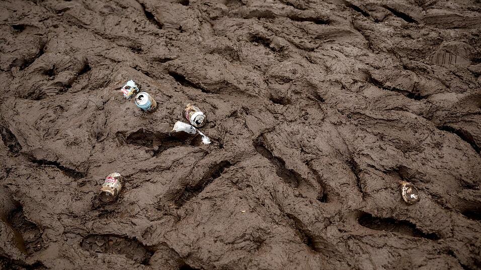 Leere Bierdosen liegen im Schlamm auf einem Festivalgelände. (Symbolbild) Leere Bierdosen liegen im Schlamm auf einem Festivalgelände. (Symbolbild)
