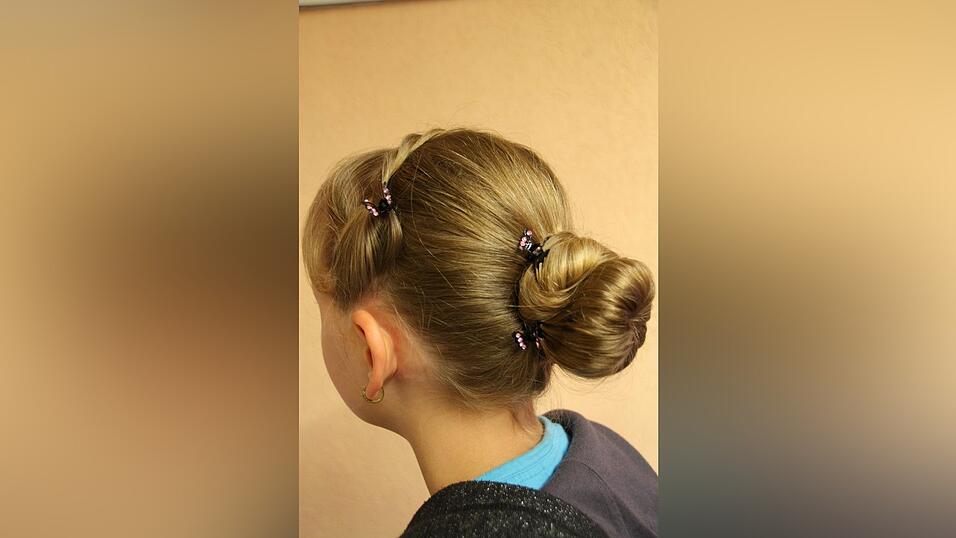 1. Leonie bindet ihre Haare zun&auml;chst mit einem Gummi zu einem Pferdeschwanz auf mittlerer H&ouml;he zusammen. An der Seitenpartie l&auml;sst sie eine dickere Str&auml;hne aus, diese wird sp&auml;ter gekordelt.