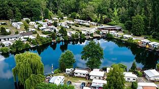 Wohnwagen auf einem Campingplatz an einem See. Manche Menschen lieben so einen Urlaub. Andere nicht. Wohnwagen auf einem Campingplatz an einem See. Manche Menschen lieben so einen Urlaub. Andere nicht.