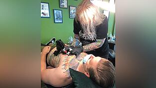 Oliver lässt die blauen Pfeilspitzen seines Brusttattoos von der Kollegin schwarz überstechen. Oliver lässt die blauen Pfeilspitzen seines Brusttattoos von der Kollegin schwarz überstechen.