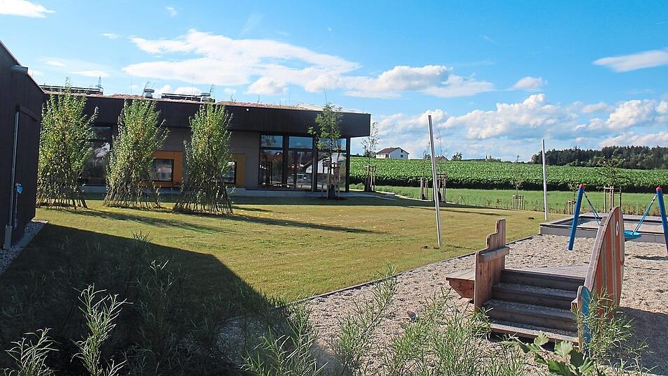 Weiden-Tipis (links auf der Wiese) bieten Platz f&uuml;r die Kleinen, auf der Sandfl&auml;che gibt es eine Vogelnestschaukel (Garten der Krippe).