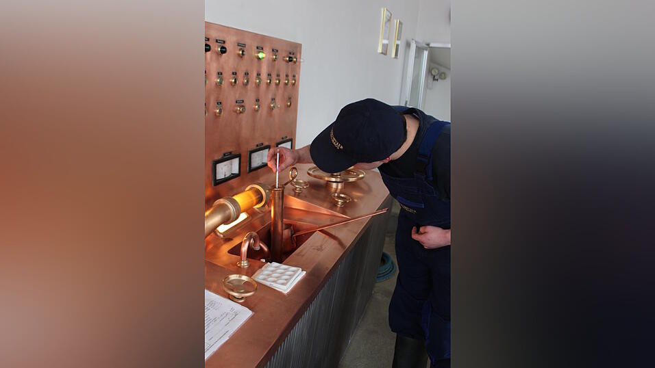 Tobias Gmeiner entnimmt aus der W&uuml;rzepfanne eine Probe und misst den Zuckergehalt. 'Das schmeckt jetzt in etwa wie s&uuml;&szlig;er Tee', wei&szlig; der Auszubildende.