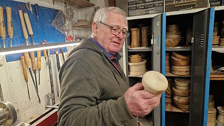 Josef Cako betrachtet einen handgemachten Schwammerl. Solche Dekoartikel sind bei den Leuten besonders beliebt, sagt er. Im Hintergrund sind weitere seiner Werke zu sehen, die er aus Spa&szlig; an der Freude fertigt. Als es immer mehr wurden, fing er vor drei Jahren an, sie auf dem Christkindlmarkt auszustellen und zu verkaufen.