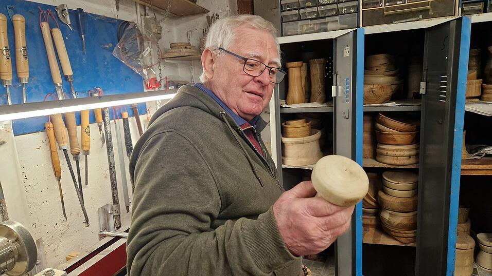 Josef Cako betrachtet einen handgemachten Schwammerl. Solche Dekoartikel sind bei den Leuten besonders beliebt, sagt er. Im Hintergrund sind weitere seiner Werke zu sehen, die er aus Spa&szlig; an der Freude fertigt. Als es immer mehr wurden, fing er vor drei Jahren an, sie auf dem Christkindlmarkt auszustellen und zu verkaufen.