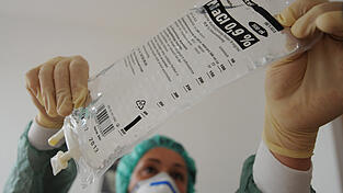 Eine Krankenschwester h&auml;ngt eine Flasche mit Kochsalzl&ouml;sung in einen Infusionsst&auml;nder. Das Mittel ist f&uuml;r die Infusion unbedingt notwendig