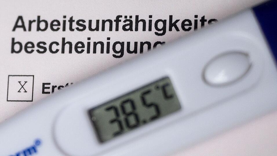 Ein Fieberthermometer liegt auf einer Arbeitsunfähigkeitsbescheinigung.
