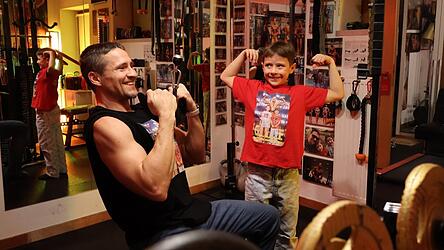 Arthur Neumann zeigt seinem Sohn Paul im Keller, der mit Dutzenden Bildern tapeziert ist, wie man eine Übung richtig ausführt.