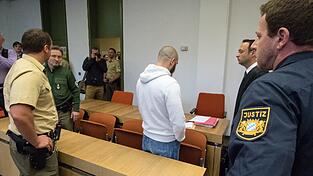 Der 27 jährige Arthur A. steht am 12.05.2016 in München (Bayern) zwischen Justizangestellten, Polizisten und seinem Anwalt Adam Ahmed (r) hinter der Anklagebank im Gerichtssaal B162 des Landesgerichts München I.