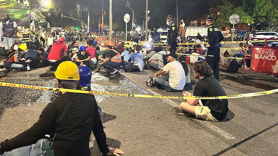 Menschen sitzen nach der Warnung wegen eines möglichen Nachbebens auf dem Boden. Menschen sitzen nach der Warnung wegen eines möglichen Nachbebens auf dem Boden.