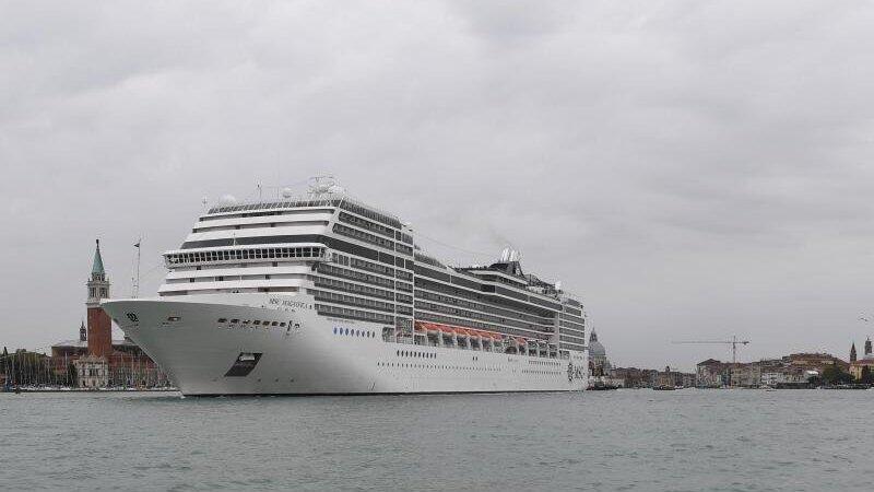 Ein Kreuzfahrtschiff fährt an der Lagunenstadt Venedig von einem Schlepper gezogen vorbei.