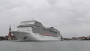 Ein Kreuzfahrtschiff fährt an der Lagunenstadt Venedig von einem Schlepper gezogen vorbei.