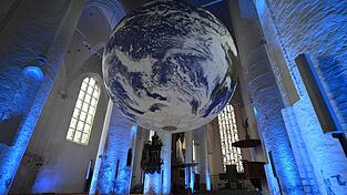 So schaut die &bdquo;GAIA&ldquo; des britischen K&uuml;nstlers Luke Jerram aus, die n&auml;chstes Jahr im M&auml;rz zum 50-j&auml;hrigen Bestehen des ZAW-SR in der Basilika St. Jakob aufgeh&auml;ngt wird. Das Bild zeigt die Kunstinstallation im Gew&ouml;lbe der Hamburger Katharinenkirche.