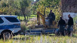 Polizisten untersuchen mit einem Bagger ein Grundstück in Herzberg (Landkreis Oder-Spree).