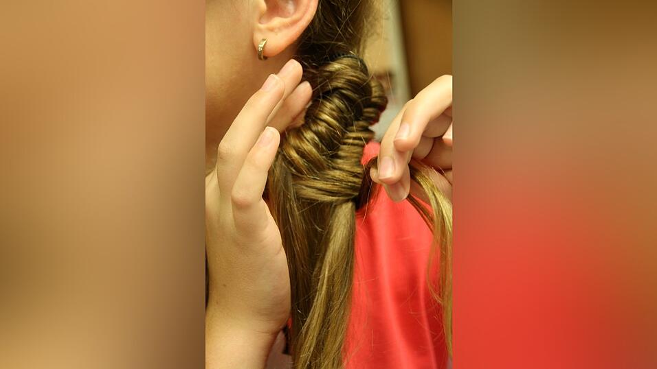 3. Den Gummi, mit dem Celina den Zopf am Anfang fixiert hat, versteckt sie unter einer Blumenspange.