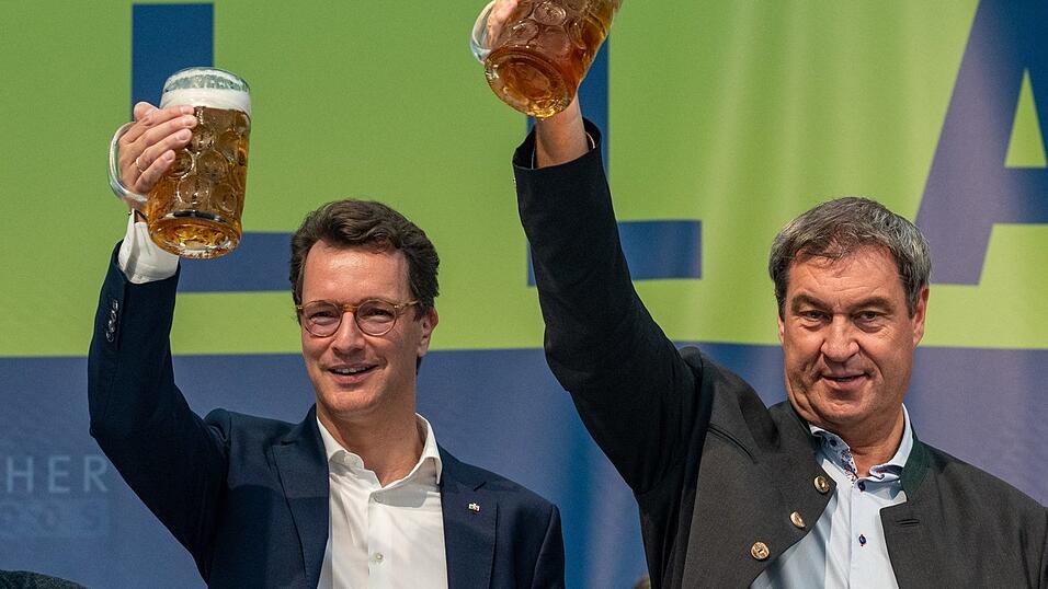 Markus Söder (r), Bayerns Ministerpräsident und CSU-Parteichef, und Hendrik Wüst, NRW-Ministerpräsident (CDU), stehen beim Politischer Frühschoppen auf dem Volksfest Gillamoos mit Bierkrügen auf der Bühne. Markus Söder (r), Bayerns Ministerpräsident und CSU-Parteichef, und Hendrik Wüst, NRW-Ministerpräsident (CDU), stehen beim Politischer Frühschoppen auf dem Volksfest Gillamoos mit Bierkrügen auf der Bühne.