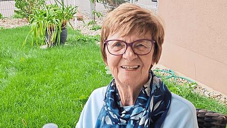 Margit Adamski sitzt auf ihrer Terasse im Garten in ihrer Erdgeschosswohnung.