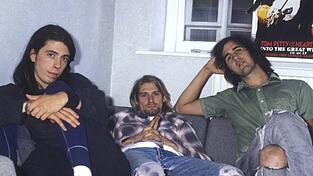 Dieses Foto der Nirvana-Bandmitglieder Dave Grohl, Kurt Cobain und Krist Novoselic entstand 1991 bei einem Interview zum Release ihres mittlerweile legendären Albums 'Nevermind'. Um das ikonische Cover ist nun ein Streit entbrannt.