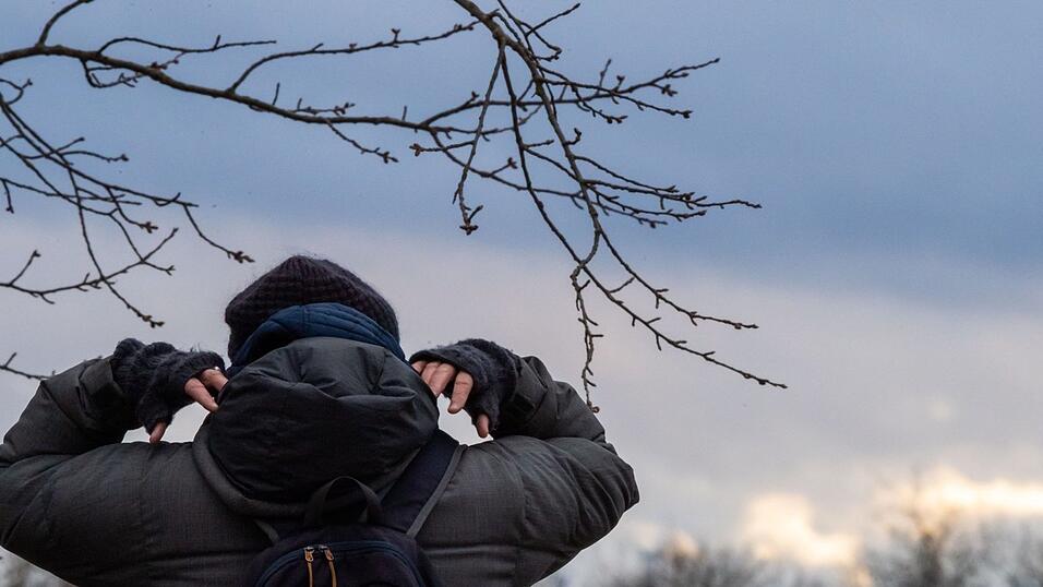 Eine Frau geht spazieren und zieht sich ihre Kapuze über den Kopf. Eine Frau geht spazieren und zieht sich ihre Kapuze über den Kopf.
