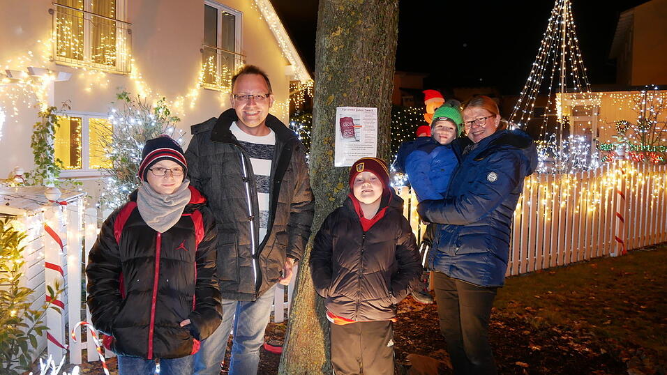 Familie Hesse vor ihrem aufwendig geschm&uuml;ckten Haus in Furth. Ein Plakat am Baum informiert &uuml;ber die Spendenaktion.