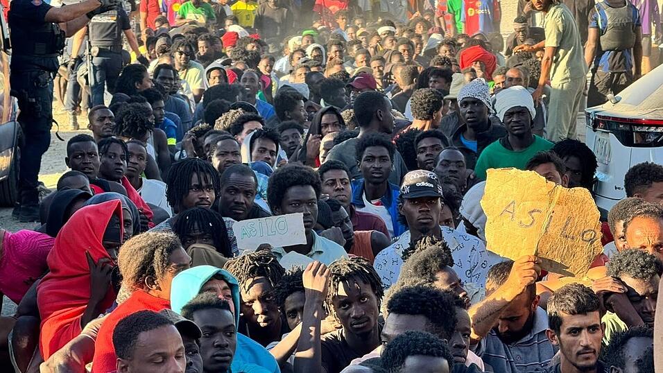 Migranten warten in einer Schlange auf Grundnahrungsmittel, die von Mitarbeitern des Roten Kreuzes und der Organisation &bdquo;Sur Sur&ldquo; verteilt werden.