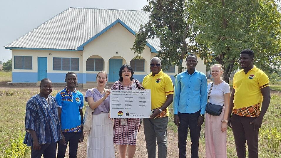 Vereinsmitglieder &uuml;bergeben die Spendertafel vor der neuen Krankenstation (im Hintergrund) an das Team des Schulzentrums. Mit den Lehrkr&auml;ften von links John Bosco, Stephen Tayo, Luise Altmann, Irmgard Hilmer, Schulleiter Pfarrer Dr. Dr. Camillo Bonsuuri, Idrussi Dawuda, Luisa Brunner und Joyous Joe Joseph.