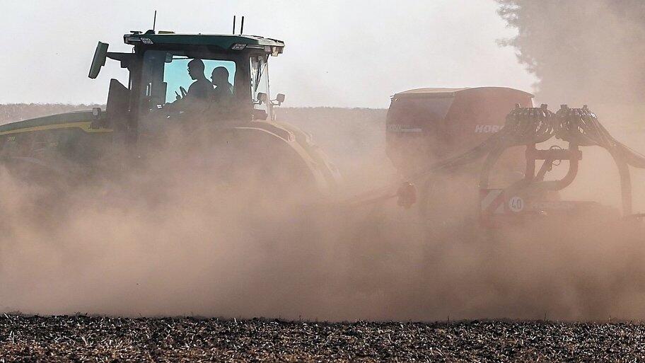 Ein Bauer wirbelt bei der Feldarbeit reichlich Staub auf. Fehlender Regen sorgt f&uuml;r trockene B&ouml;den auf den Feldern.